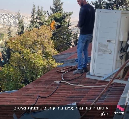 אדם על גג עם מבער להלחמת יריעות איטום